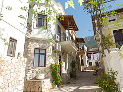 Thin alley in Kalkan Old Town with traditional townhouses on either side shaded from the sun